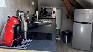 Een kleine keuken met een rode koffiezetapparaat, een inbouwoven en een koelkast.