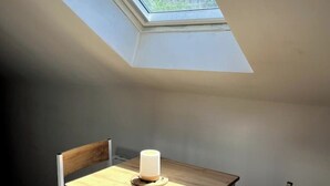 Een kamer met een dakvenster, een houten tafel en een stoel.