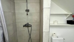 Een badkamer met douche, toilet en een plank met toiletartikelen.
