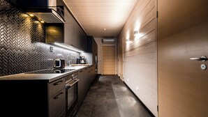 A modern kitchen with a herringbone tile backsplash, stainless steel appliances, and wooden cabinetry. - Parkside Pyhä (Pelkosenniemi)