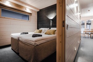 Un dormitorio moderno con cama, paredes de madera, una ventana y una zona de comedor.