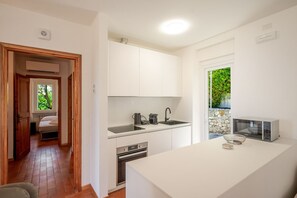 A compact kitchen with white cabinets, a built-in oven, a microwave, and a sink. - ApartmentsGarda - Albisano Sky House (Torri del Benaco)