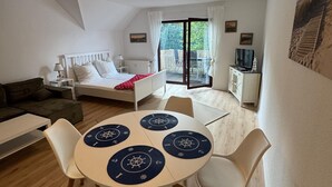 A cozy room with a bed, a dining table with placemats, a sofa, and a TV. - Vacation apartment with balcony  (Gustow)