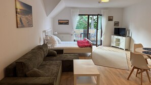 A modern room with a bed, a sofa, a small table, and a TV. - Vacation apartment with balcony  (Gustow)