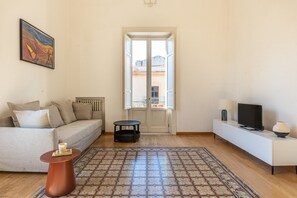 Una sala de estar con sofá, una mesa de centro, televisor y un tapete estampado.