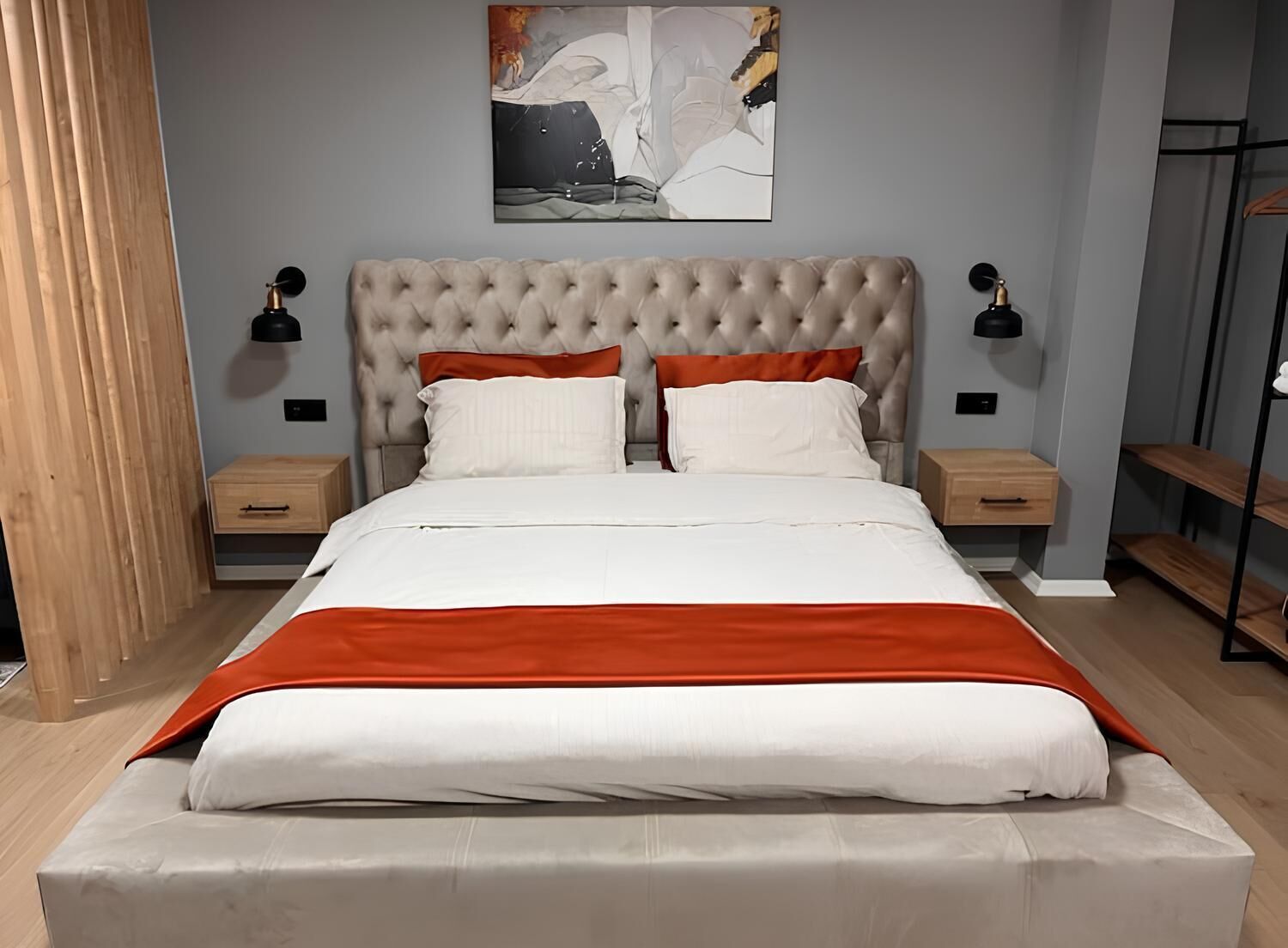 Ein modernes Schlafzimmer mit einer gepolsterten Kopfteil, weißer Bettwäsche und roten Akzenten.