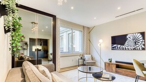 A modern living room with a sofa, a round coffee table, and a large window. - MONTAIGNE EXECUTIVE SUITE (Paris)