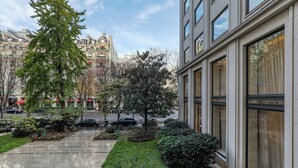 A modern building with a Louis Vuitton store on the ground floor, surrounded by well-maintained gardens and a clear view of the street. - MONTAIGNE EXECUTIVE SUITE (Paris)