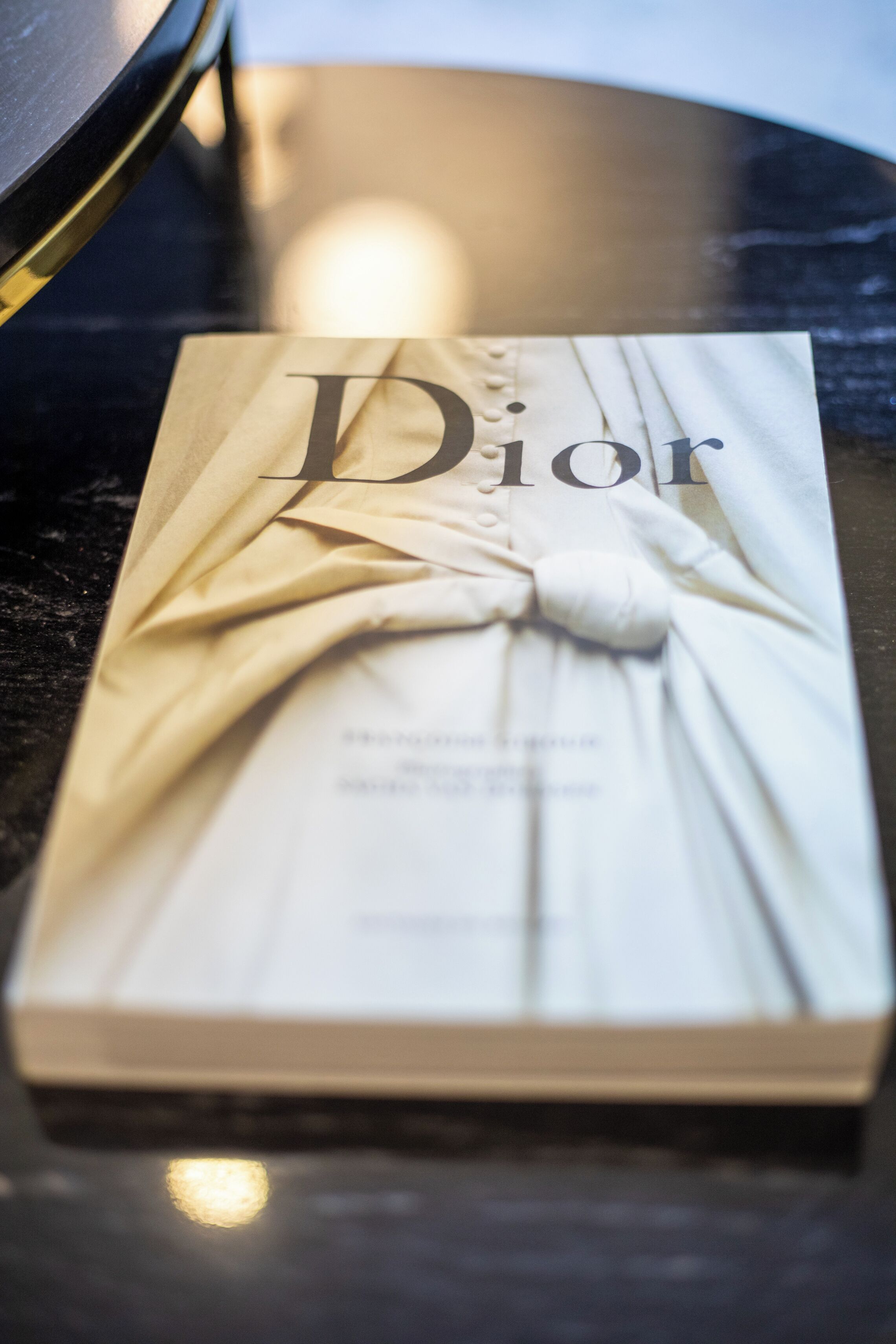A book titled 'Dior' on a reflective surface.