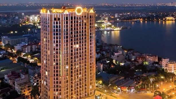 A high-rise hotel with a central courtyard, surrounded by a cityscape and a body of water.