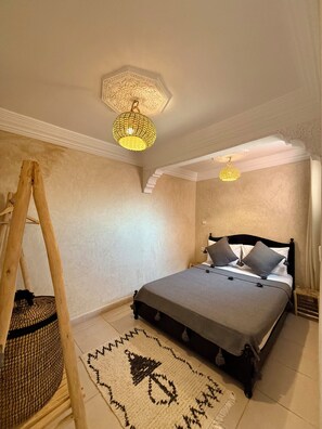 Ein Schlafzimmer mit einem Bett, einer Holzleiter, einem gewebten Korb und einem gemusterten Teppich.