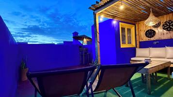 Eine Dachterrasse mit einer Holz-Pergola, einem Tisch und Stühlen.