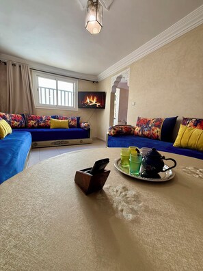 Ein Wohnzimmer mit zwei Sofas, einem Couchtisch, einem Fernseher und einem Kamin.