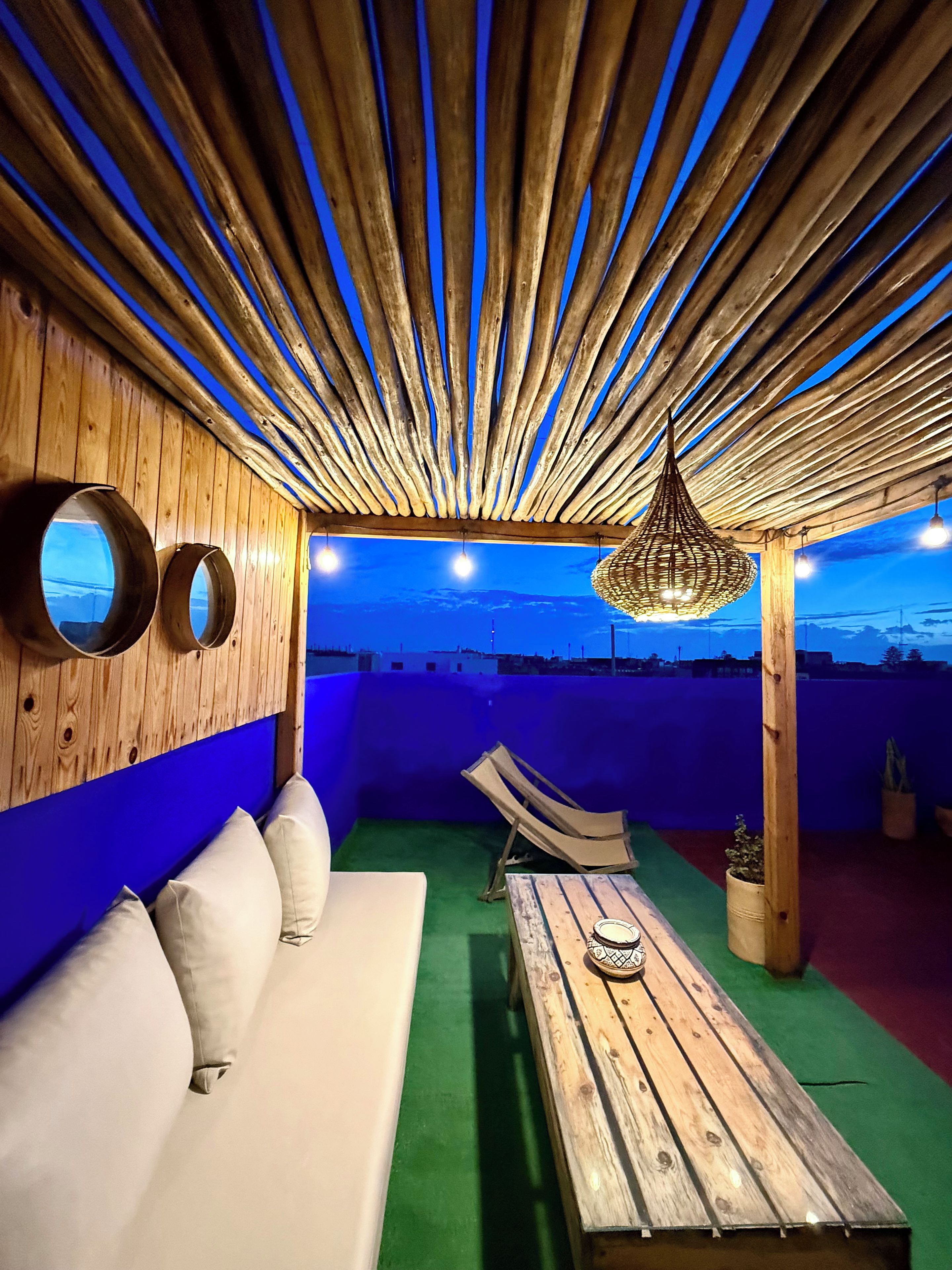 Un salon sur le toit, avec un plafond en bois, un canapé, une table et une vue sur le paysage urbain.