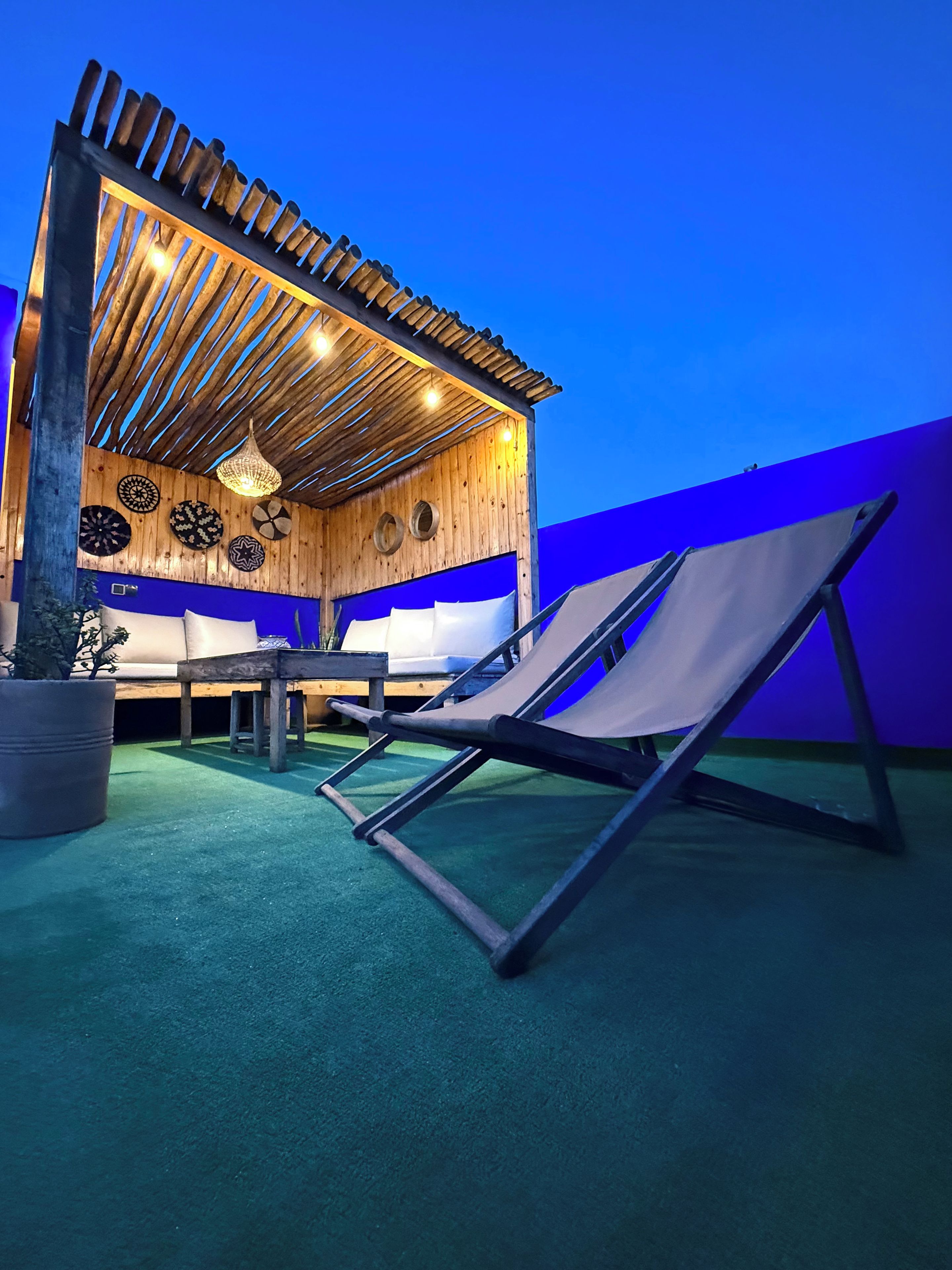 An outdoor seating area with a table and chairs, a pergola structure, and decorative wall plates.