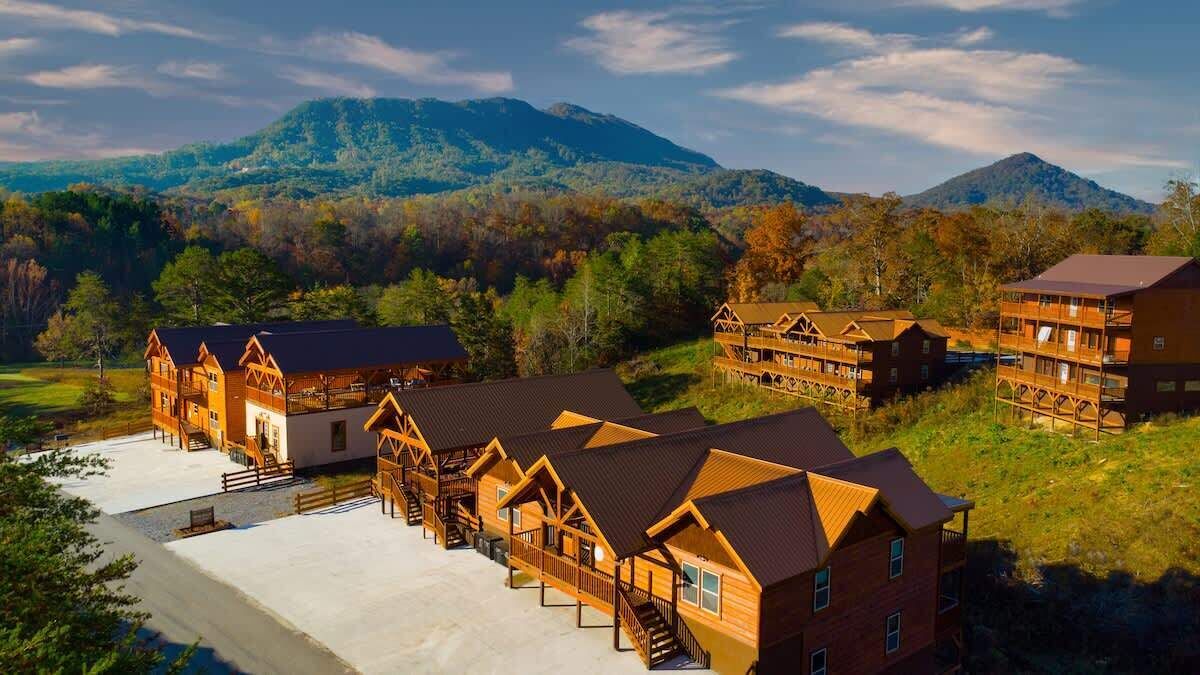 Eine Lodge mit mehreren Holzhäusern, einem überdachten Außenbereich und einem Bergpanorama.