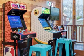 Arcade machines with a wooden backdrop and a view of the outside. - 8-Bedroom Smoky Mountain Cabin with Indoor Pool, Outdoor Theater & Arcade (Sevierville)