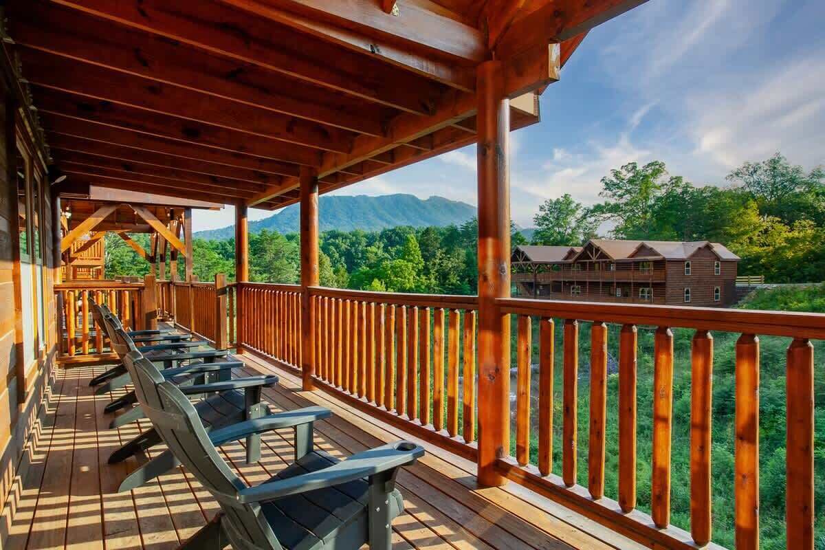 Una terraza de madera con bancos que da a un paisaje montañoso y un edificio de alojamiento.