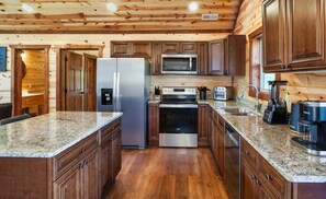 Eine moderne Küche mit Granit Arbeitsplatten, Edelstahlgeräten und Holzschränken.