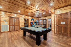 Ein Billardtisch in einem Holzraum mit Deckenventilatoren und Spielautomaten.