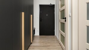 En hall med en mörk dörr, en ljusströmbrytare och ett eluttag på väggen.