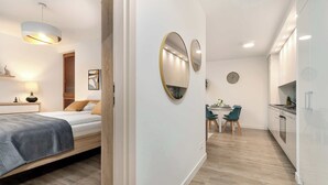 Ett modernt och kompakt bostadsutrymme med en säng, en matplats och ett litet kök.