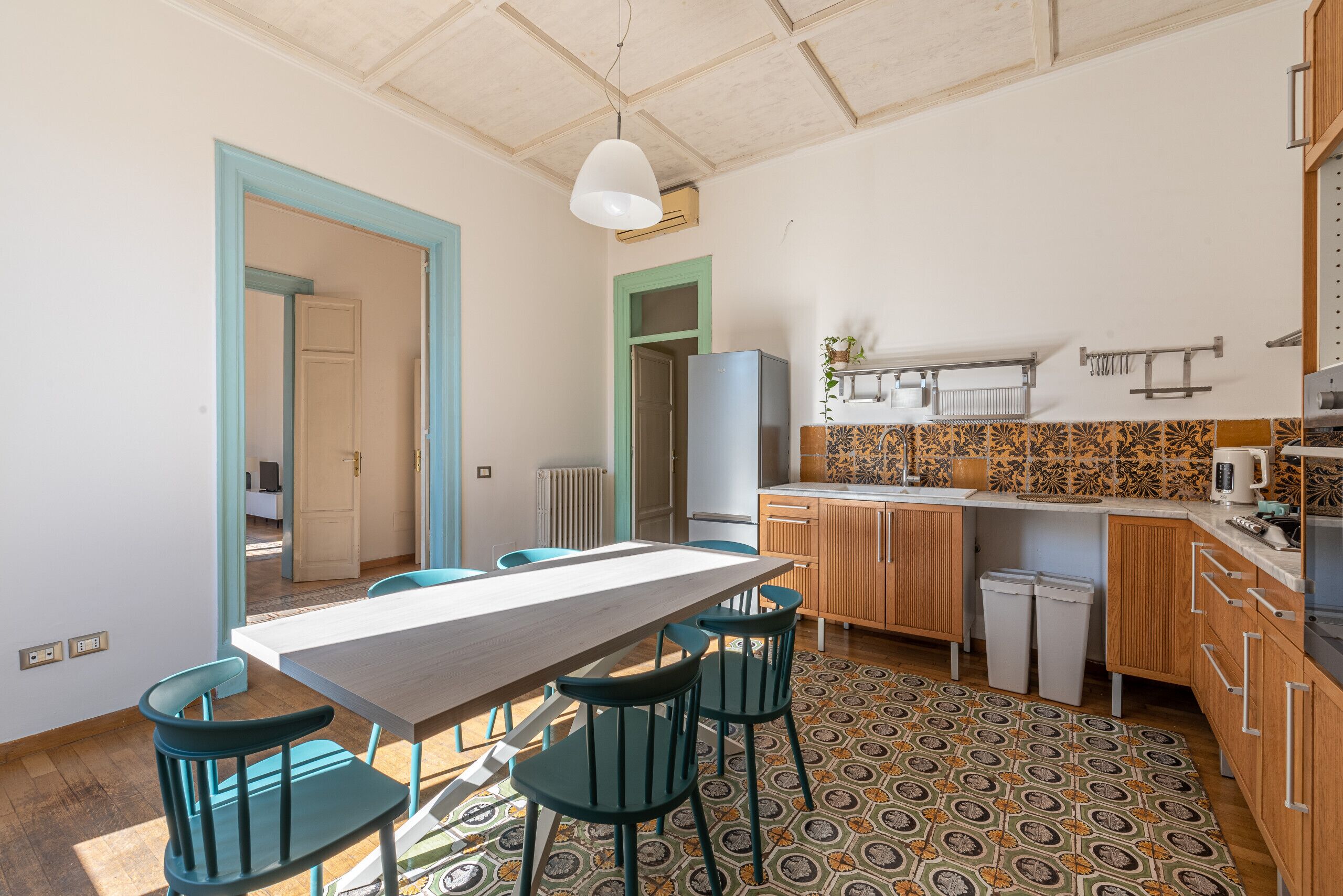 Une cuisine moderne dotée d’un grand îlot central, d’un coin repas avec une table et des chaises, et d’un sol à motifs.