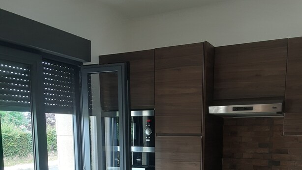 A modern kitchen with wooden cabinets, a stainless steel refrigerator, and a built-in oven.