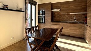 A modern kitchen with wooden cabinets, a built-in oven, and a dining table with chairs.