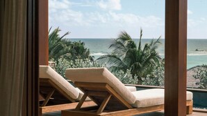 Un pontile di legno con poltrone relax vista spiaggia e oceano.