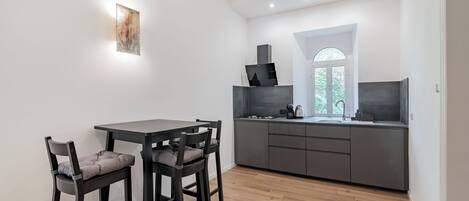 Une cuisine moderne avec un plan de travail foncé, une cuisinière encastrée et une fenêtre donnant sur un paysage verdoyant.