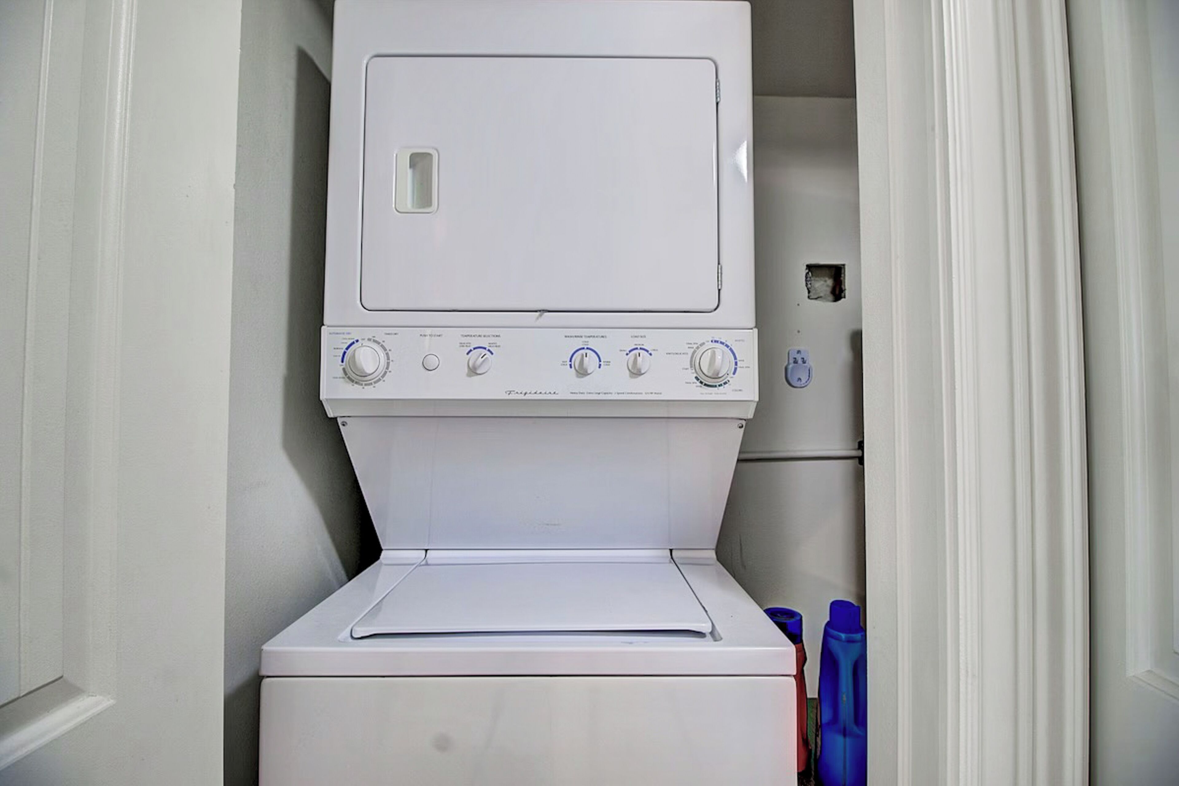 Un appareil compact, blanc, combinant lave-linge et sèche-linge à chargement frontal, doté de boutons de commande et d’une petite fenêtre sur le dessus.