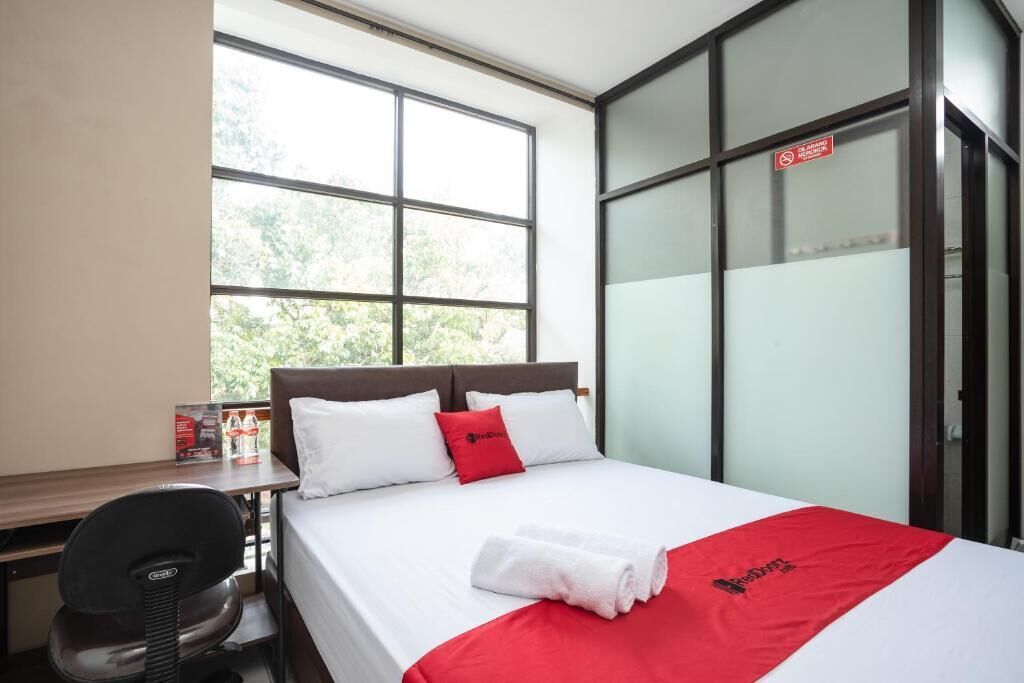 A hotel room with a bed, a desk, a chair, and a window.