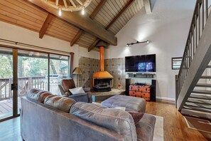 A cozy living room with a fireplace, leather sofas, a TV, and a wooden deck. - Walk to Golf & Restaurants: Serene Twain Harte Gem (Twain Harte)