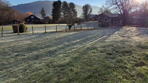 A rural landscape with a clear sky, a frost-covered field, and a few buildings in the background.
