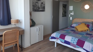 Ein Schlafzimmer mit Bett, Schreibtisch, Stuhl, Kleiderschrank und Klimaanlage.