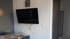 Ein moderner Essbereich mit einem an der Wand befestigten Flachbildfernseher, einem Esstisch mit Stühlen und einer Zimmerpflanze.
