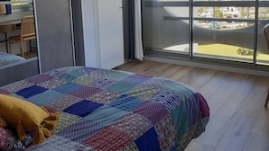 Ein Schlafzimmer mit einem großen Bett, Blick auf einen Yachthafen und einem Balkon mit Blick auf den Yachthafen.