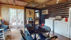 A rustic cabin interior with a dining table, chairs, a washing machine, and a wooden ceiling. - Adirondacks in Style! Lake House w/ Deck, Fire Pit (Lake Luzerne)