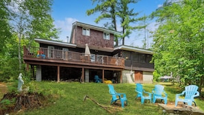 A two-story house with a deck, outdoor seating area, and a statue. - Adirondacks in Style! Lake House w/ Deck, Fire Pit (Lake Luzerne)