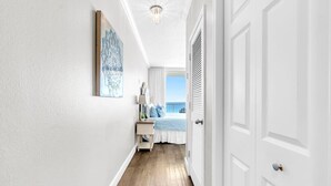 A hallway with a bed, a nightstand, and a view of the sky. - BeachFront-5 Pools,Starbucks, Theater@Majestic 612 (Panama City Beach)