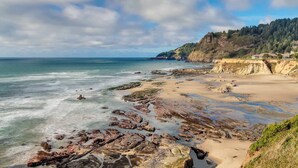 Un paisaje costero con un litoral rocoso, una playa arenosa y un acantilado boscoso.
