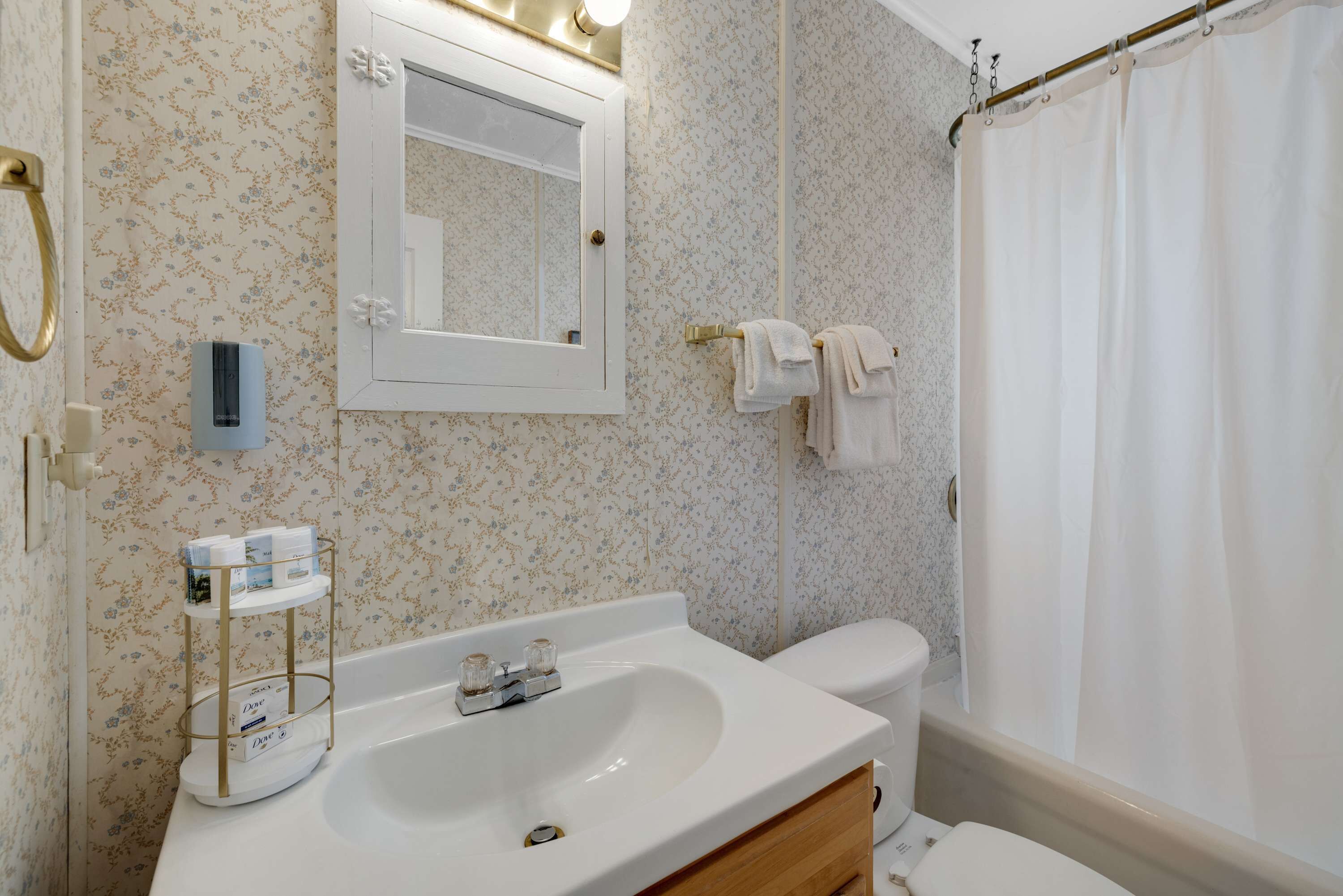 A bathroom with a white sink, a mirror, a toilet, and a shower curtain.