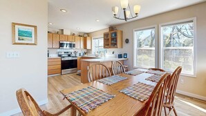 Una cocina moderna con armarios de madera, una isla central y un comedor con mesa y sillas de madera.