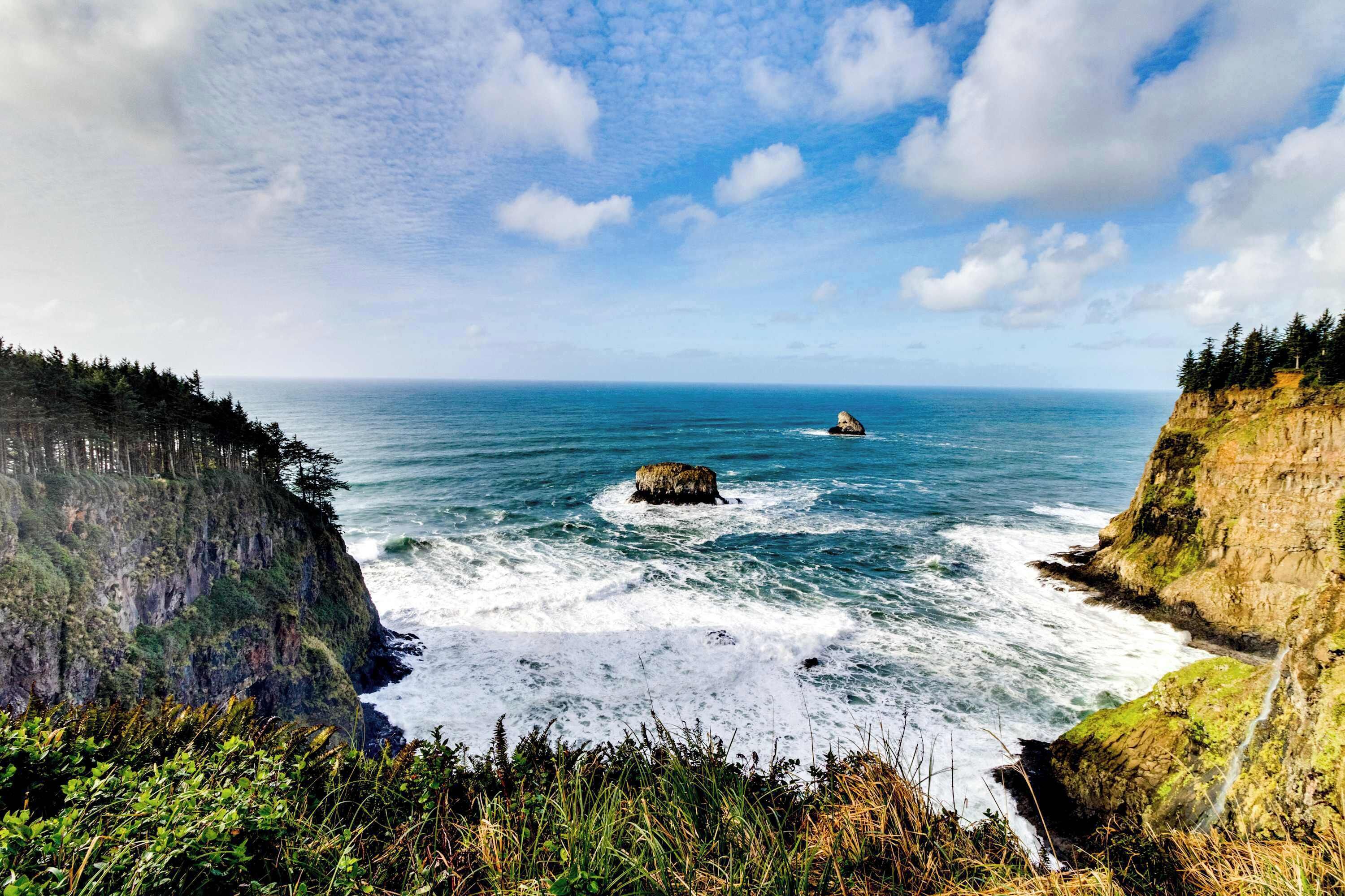 A coastal landscape with cliffs, ocean waves, and a clear sky.