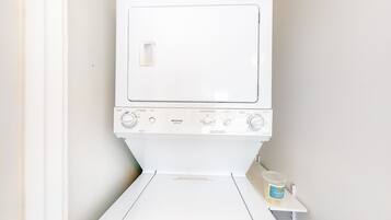 Eine weiße, robuste Waschmaschine und Trockner-Kombination von Frigidaire mit Bedienfeld, Dosierfach und einer kleinen Ablagefläche mit Behälter.