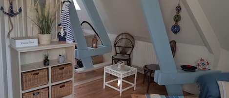 A nautical-themed room with a high ceiling, a wooden bench, a small table, wicker baskets, and a tissue box labeled "Tissue Box".