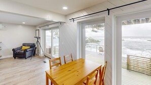 A spacious living area with a wooden dining table and chairs, a black leather chair, and a tripod. - Oceanfront dog friendly home with coastal views telescope walkable location (Depoe Bay)