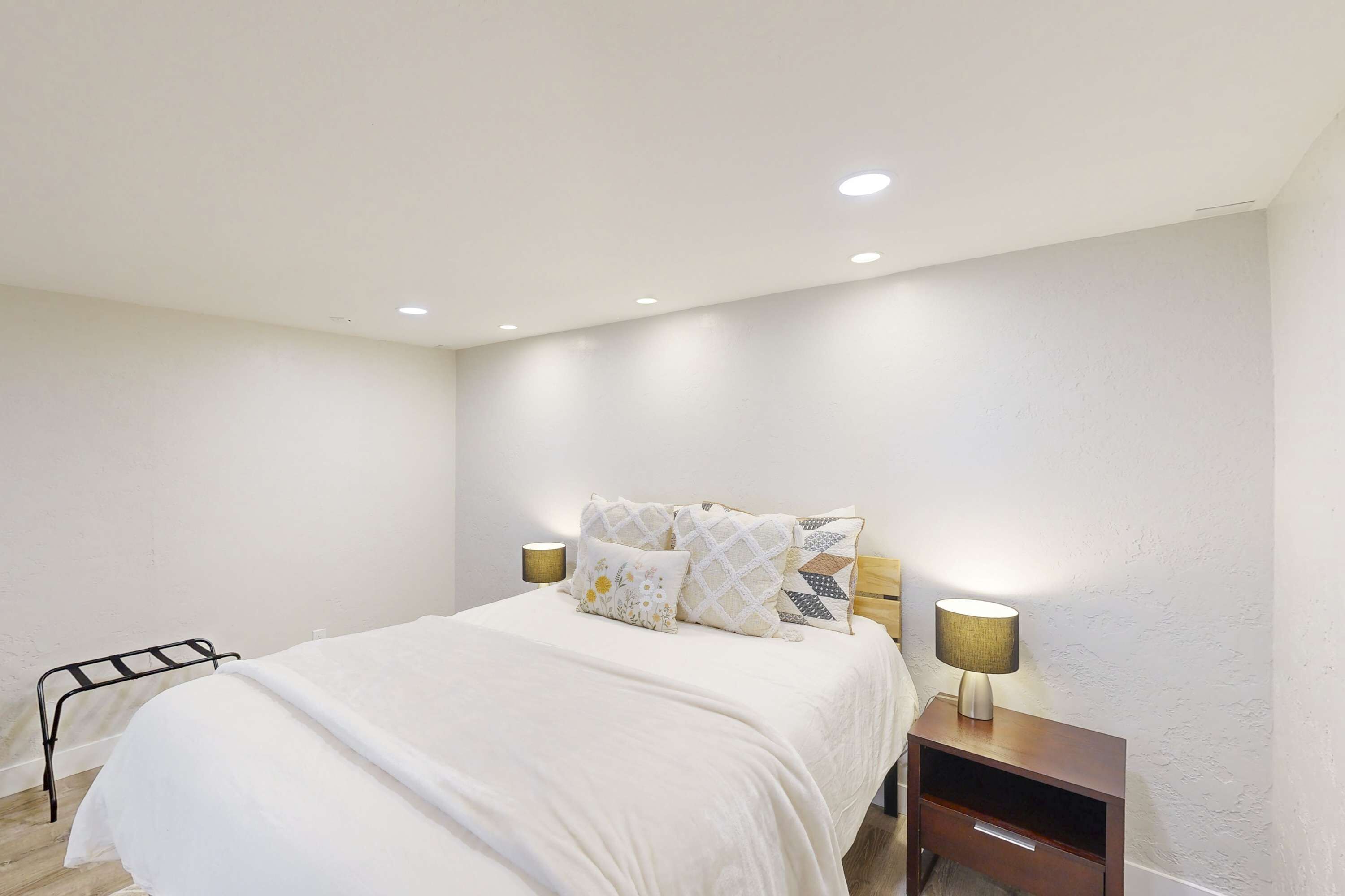 A bedroom with a bed, two bedside tables, and a nightstand.
