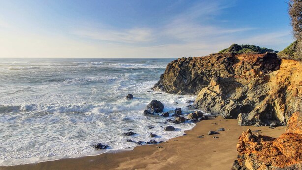 A coastal landscape with a rocky cliff and sandy beach. - Oceanfront dog friendly home with coastal views telescope walkable location (Depoe Bay)